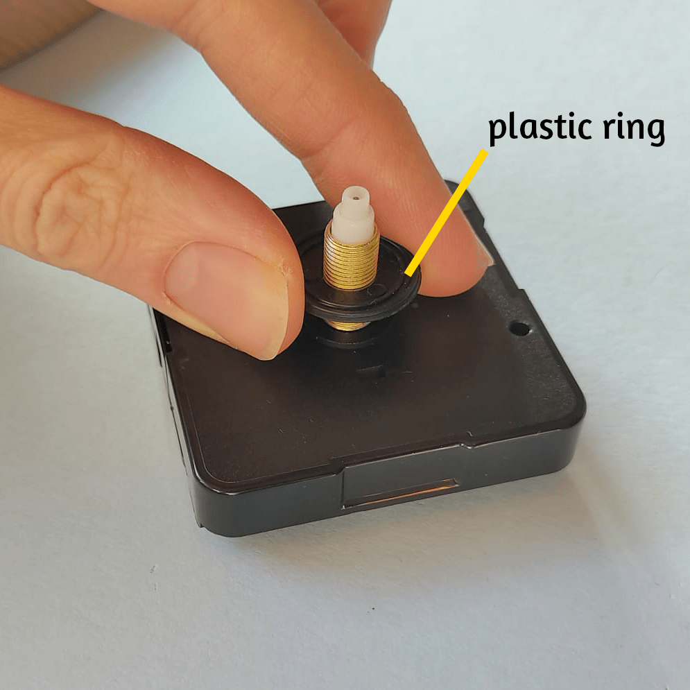 Voordat je de houten klok op het uurwerk legt, plaats je de zwarte plastic ring.