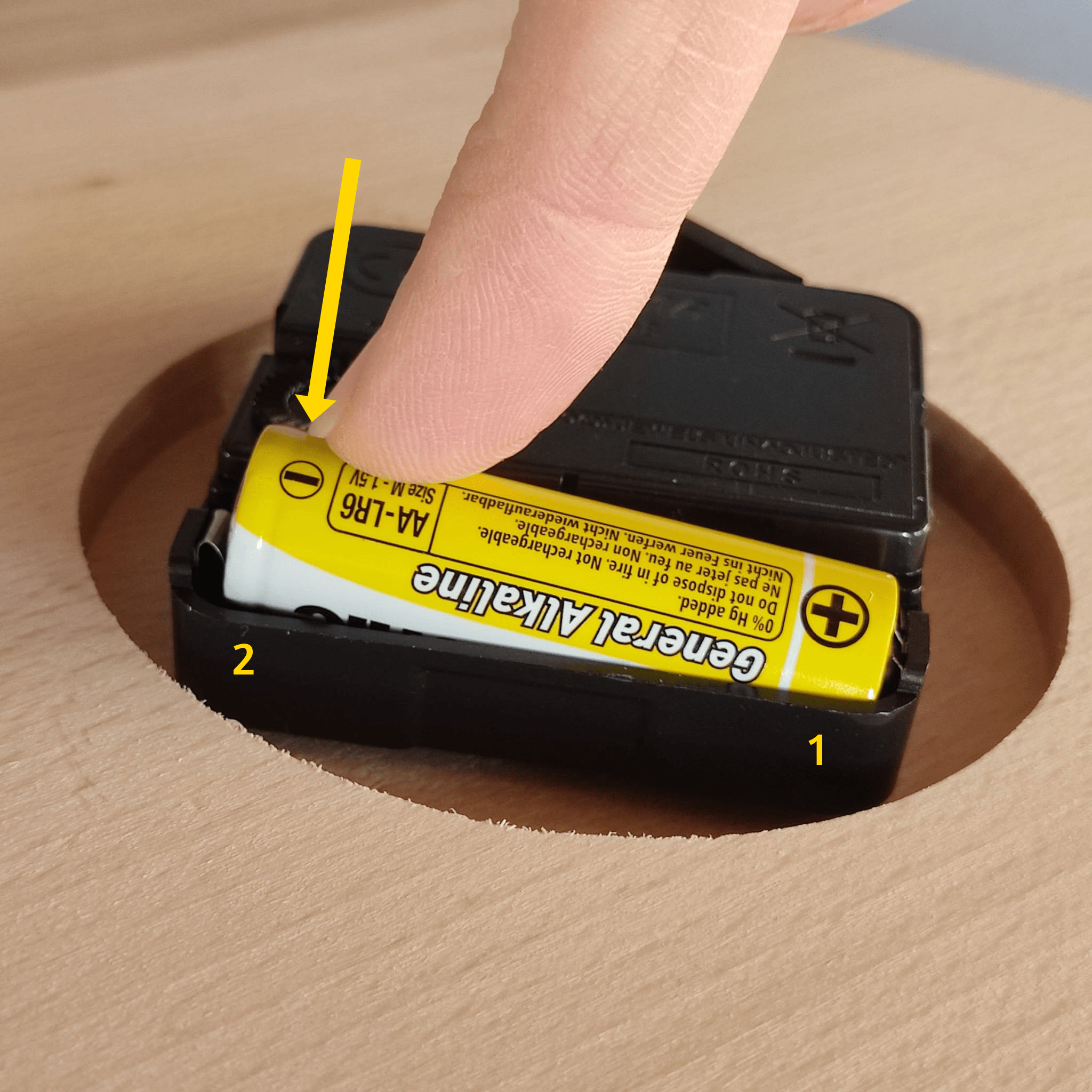 De batterij plaats je eenvoudig door eerst de plus kant in het uurwerk te plaatsen en vervolgens druk je op de min kant totdat de batterij in het uurwerk zit.